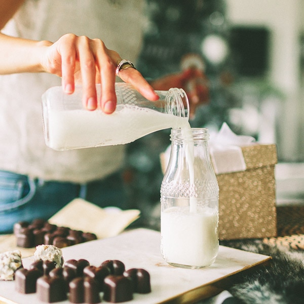 A woman pours milk from one glass jar to another. A woman pours milk from one glass jar to another.