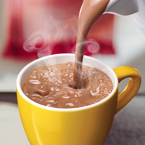 Un humeante chocolate caliente se vierte en una taza color amarillo.{ Un humeante chocolate caliente se vierte en una taza color amarillo.{