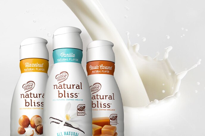 Tres botellas de creamer y leche vertiéndose detrás de ellas.