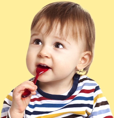 Un niño pequeño con camisa a rayas muerde una cuchara roja.