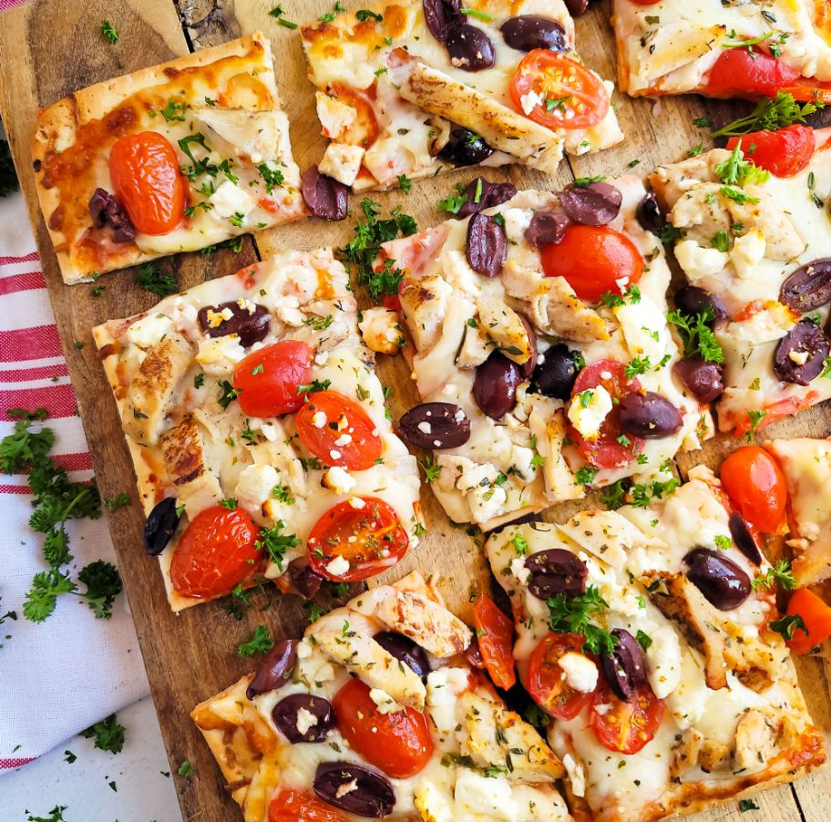 A DiGiorno Four Cheese Thin Crust pizza topped with chicken, feta cheese, kalamata olives and cherry tomatoes.