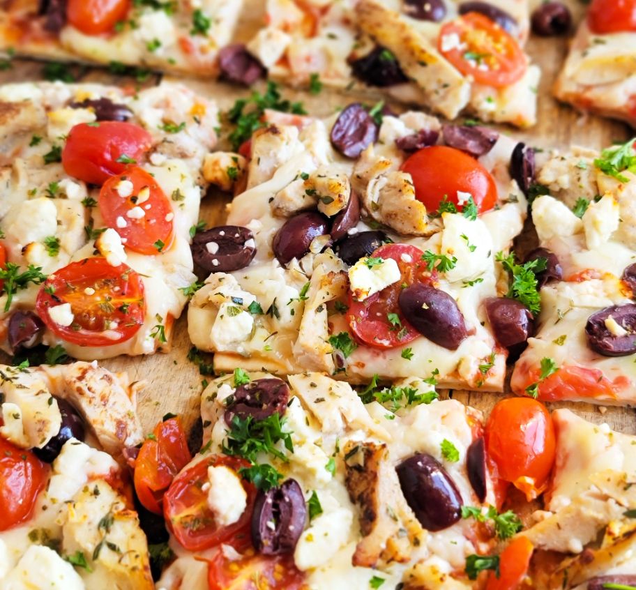 A DiGiorno Four Cheese Thin Crust pizza topped with chicken, feta cheese, kalamata olives and cherry tomatoes.