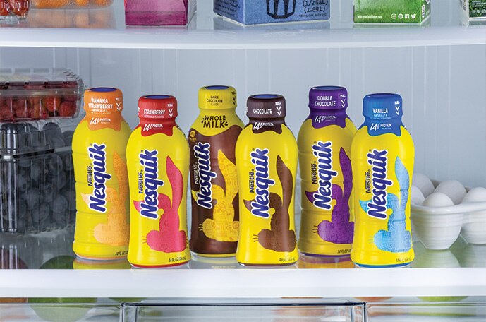 Bottled strawberry banana, strawberry, dark chocolate, chocolate, double chocolate and vanilla flavored milks in the fridge.
