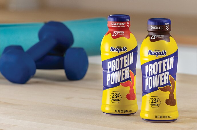 Bottles of strawberry and chocolate Nesquik Protein Power set next to a yoga mat and weights.