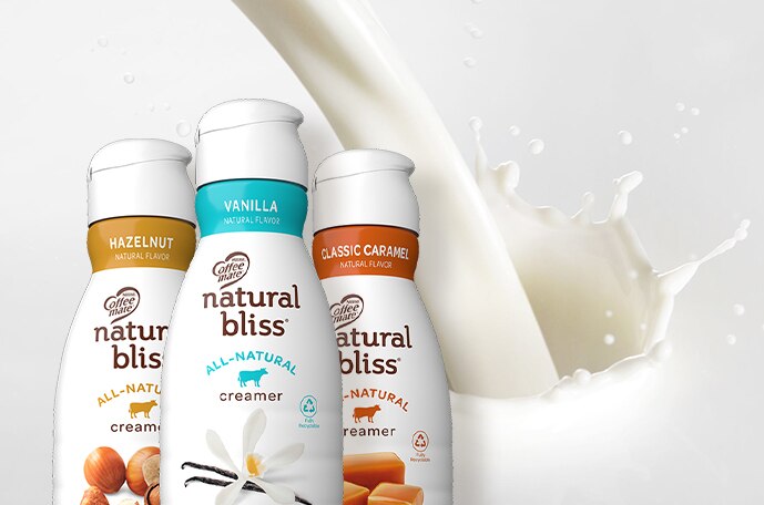 Three bottles of natural bliss creamer with creamer splashing behind them.