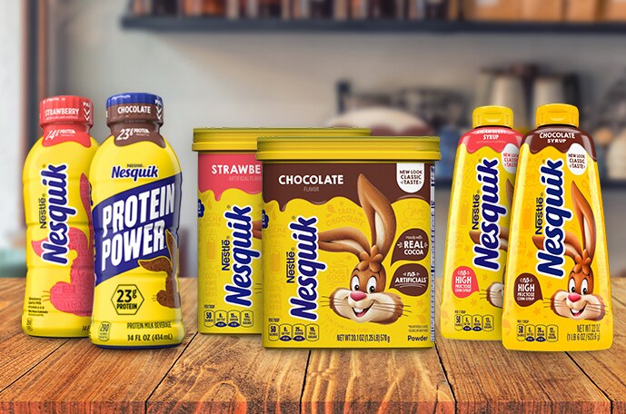 Bottles and canisters of chocolate and strawberry Nesquik milk, syrup and powder on a kitchen counter.