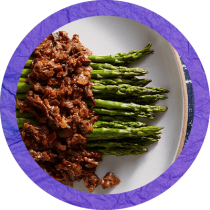 Circle cropped image of asparagus topped with brown morel sauce surrounded by a purple textured circle. Circle cropped image of asparagus topped with brown morel sauce surrounded by a purple textured circle.