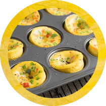 Circle cropped image of muffin tin egg bites with green onion and red pepper in a muffin tin surrounded by a pink textured circle. Circle cropped image of muffin tin egg bites with green onion and red pepper in a muffin tin surrounded by a pink textured circle.