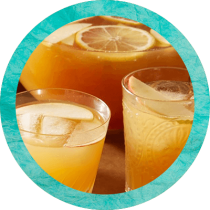 A punch bowl and two glasses filled with apple cider sangria and sliced apples and lemons. A punch bowl and two glasses filled with apple cider sangria and sliced apples and lemons.