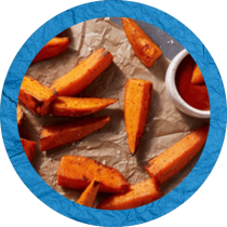Circle cropped image of sweet potato wedges on brown crinkled paper with a ramekin filled with creamy sriracha ketchup on the side surrounded by a purple textured circle. Circle cropped image of sweet potato wedges on brown crinkled paper with a ramekin filled with creamy sriracha ketchup on the side surrounded by a purple textured circle.