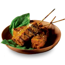 Skewers of sliced Curry Seitan in a wooden bowl with basil leaves.