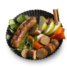 Plant-Based Sausage link besides sliced sausage, spinach, red pepper slices, apple slices, and a cinnamon stick in a soufflé dish