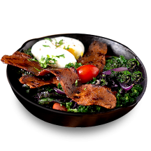 A black bowl with fresh greens, a soft boiled egg and pieces of benevolent bacon.