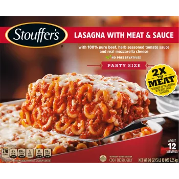 A spatula lifts Lasagna with Meat & Sauce from a red dish on a table with the product name and "2x the Meat" label.