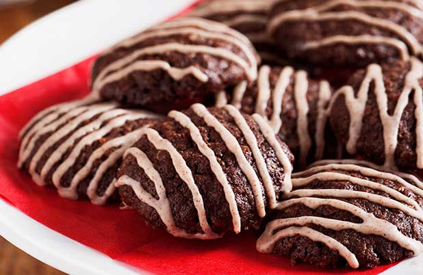 Chocolate cookies with white icing on a plate and red napkin.