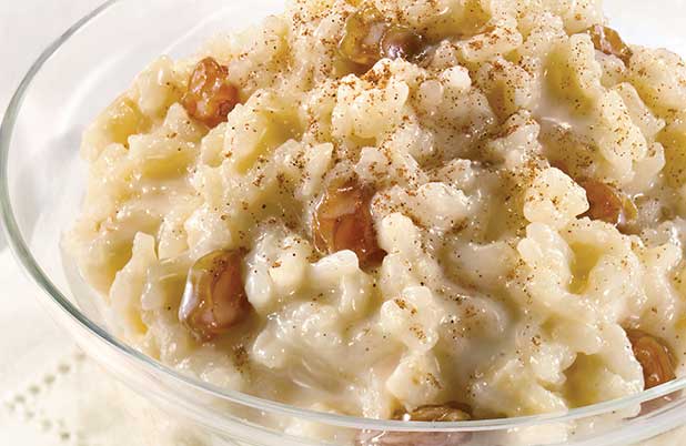 A clear dish of rice pudding with golden raisins.