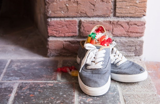 Un par de zapatos llenos de dulces junto a una chimenea de ladrillo.