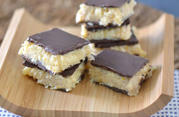 Chocolate coconut bars on a curved wooden serving tray.