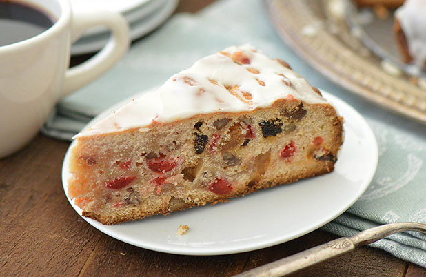 A slice of paneton filled with dried fruit and nuts on a plate with a fork.