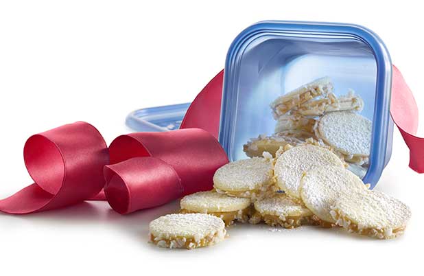 Sandwich cookies spill out of a resealable plastic container with large red ribbon.