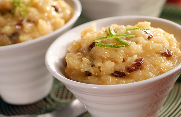 Small white dishes filled with rice pudding topped with lime garnish and raisins.