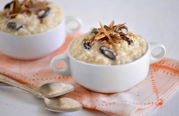 Two ceramic dishes filled with Domican Rice pudding topped with raisins and cinnamon sticks.