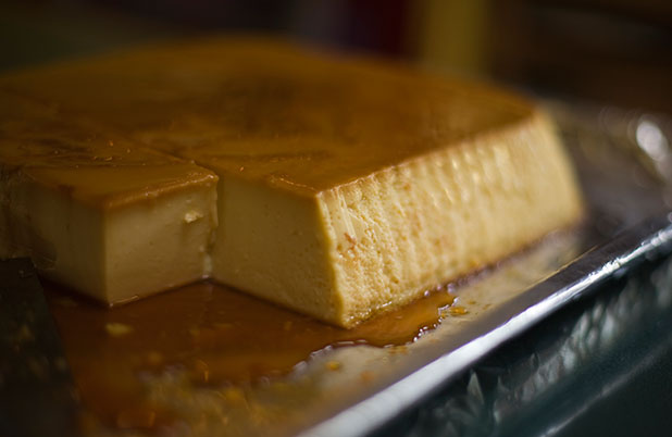 A rectangular flan on a sheet pan with caramel on top and beneath.