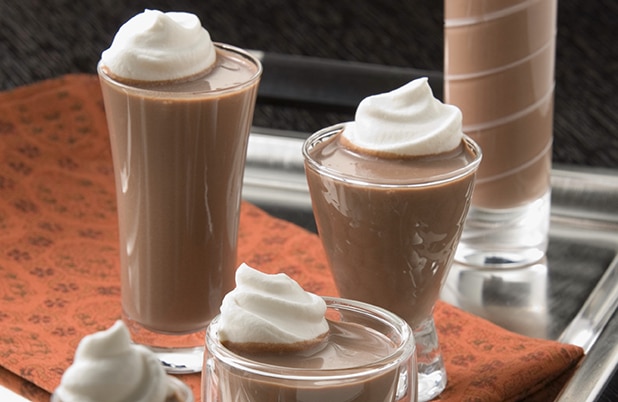 Tall shot glasses filled with hot peppermint mocha shots topped with whipped cream.