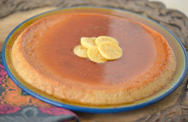 A thin flan topped with guava slices on a ceramic plate.