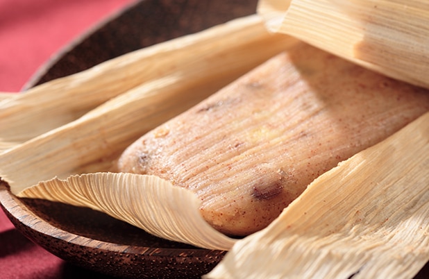 Un tamal dulce abierto con motitas de canela.