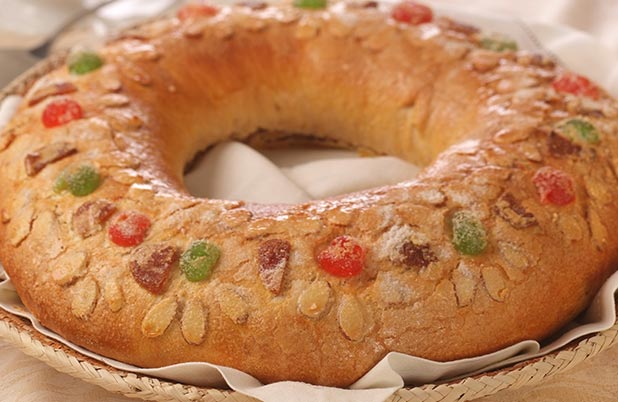 A ring of Three Kings Bread with red and green fruit garnish on the bread.