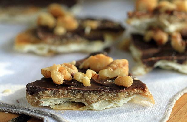 Saltine toffee topped with chopped nuts cooling on a cloth napkin.