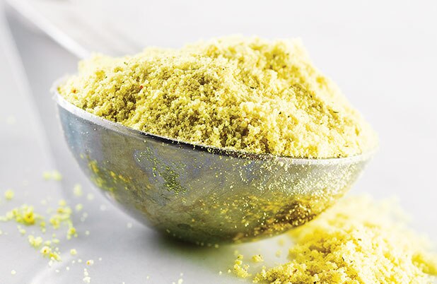 A measuring spoon spilling over with masa harina.