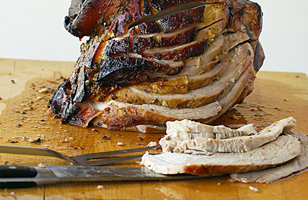 Turkey sliced on a carving board beside a fork and carving knife.