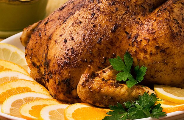 A whole turkey on a platter surrounded by orange slices.