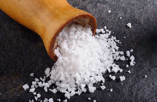 A pile of salt from a salt shaker on a black surface.