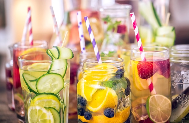 Various jars and glasses filled with fresh fruit, ice and straws.