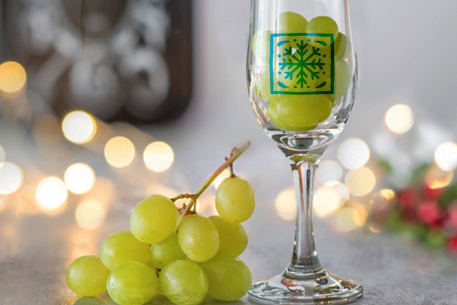 Bunches of grapes on a counter with lights and a champagne glass filled with grapes.