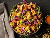 Vibrant salad with planted-based Chik’n, purple cabbage & avocado in rustic bowl on a black, natural stone background