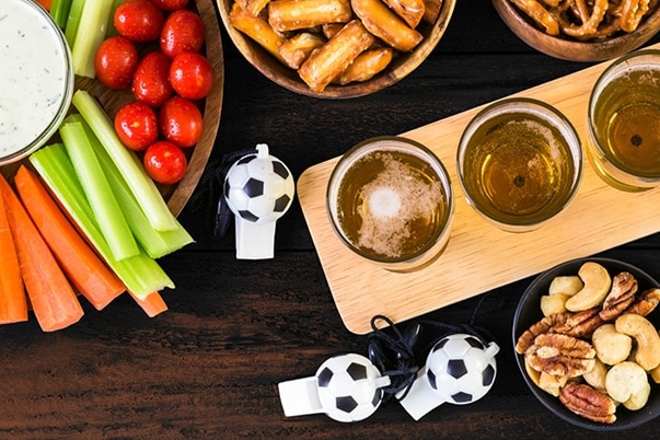 A vegetable tray, bowls of nuts, bowls of pretzels, football-shaped whistles.