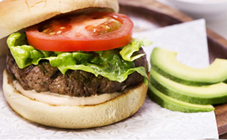 Photograph: hamburger with beef patty, lettuce, tomato; avocado slices beside it