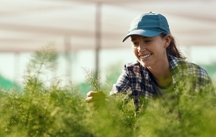 Una agricultora sonríe mientras inspecciona una cosecha verde.