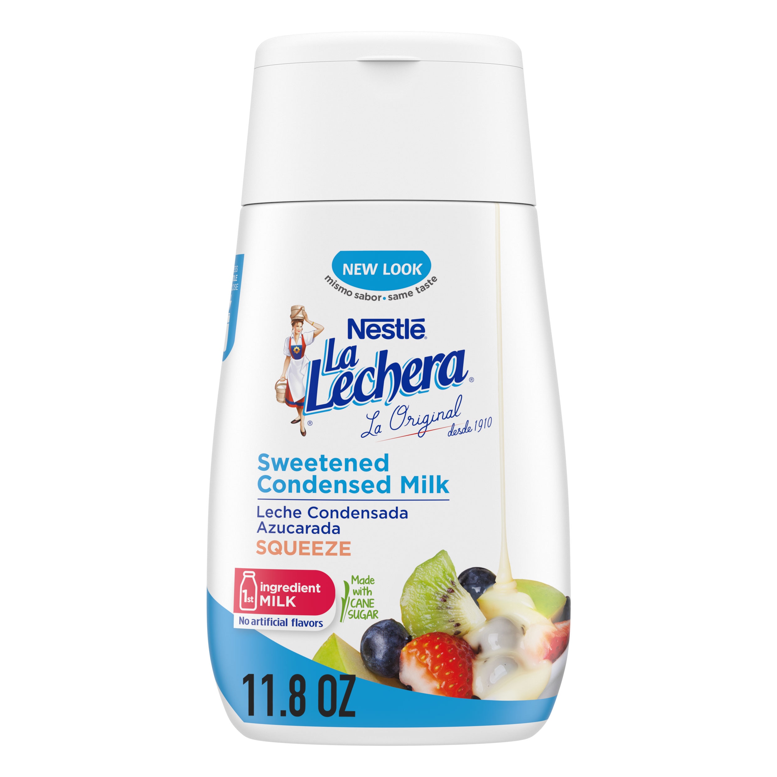 Una botella sirve fácil con una tapa color azul con el logo de La Lechera, junto a una pila de fruta rociada con leche condensada azucarada.
