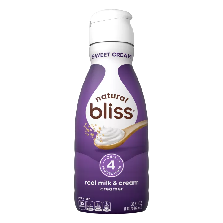 White bottle of natural bliss Sweet Cream flavored Creamer with a purple label above a spoon of sugar and swirl of milk.