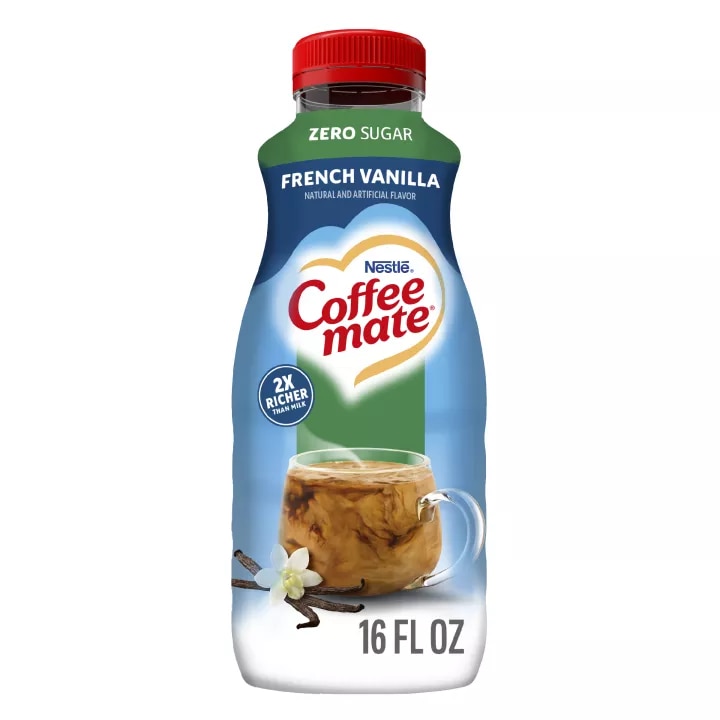 Una botella azul de creamer Zero Sugar French Vanilla que lee sin azúcar sobre una taza de café y granos de vainilla.