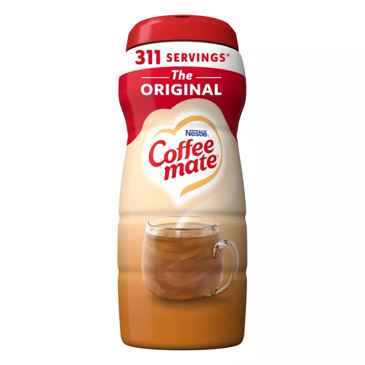 Una lata de creamer Coffee mate Original con una etiqueta roja, una taza de café, un biscotti y el logotipo de Coffee mate.