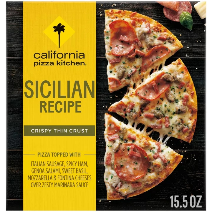 Caja de pizza Sicilian Recipe con media pizza, salami, albahaca, pepperoni y parmesano sobre una superficie de madera negra.
