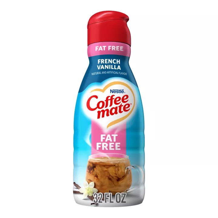 A bottle of French Vanilla Liquid Creamer with a red cap and pink "Fat Free" label above a mug and vanilla beans.