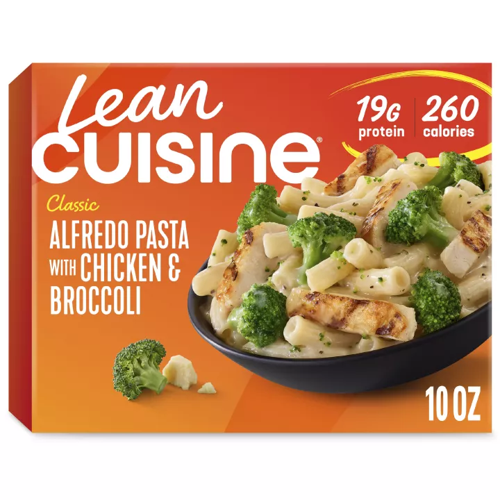 A box of Alfredo Pasta with Chicken & Broccoli with a Comfort Cravings label near a bowl of pasta with chicken and Alfredo sauce.