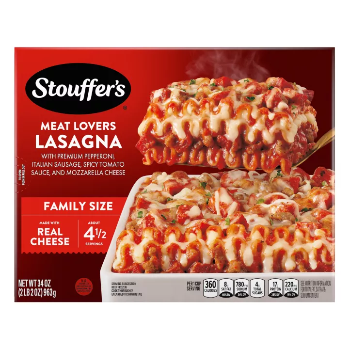 Caja de Meat Lovers Lasagna con un plato de lasaña cerca de un plato, el nombre del producto, el logo de STOUFFER'S y una etiqueta que dice "TAMAÑO FAMILIAR".